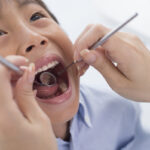 A young boy is examined for dental caries.