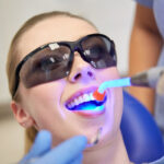 A UV light cures or hardens a dental resin applied during a tooth bonding procedure.
