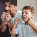 Father and son cleaning teeth with dental floss