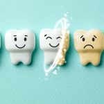 Image of 5 teeth. Half are smiling and bright white while the other half are sad and yellowed. They lay against a soft turquoise background. The image signifies the process of teeth whitening.